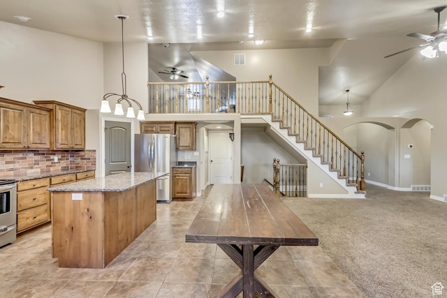 995 W 2650 S, Perry, UT 84302 - kitchen featuring ceiling fan, appliances with stainless steel finishes, high vaulted ceiling, a center island, and brown cabinets