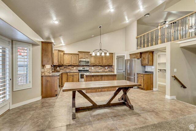 995 W 2650 S, Perry, UT 84302 - kitchen with appliances with stainless steel finishes, decorative backsplash, a kitchen island, lofted ceiling, and baseboards