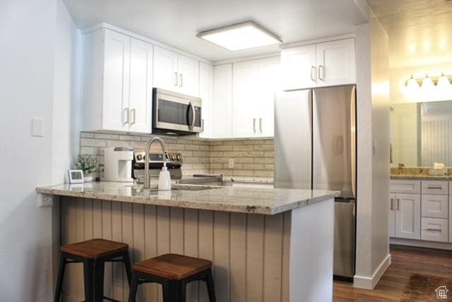 385 S Vasels Rd Unit 21, Brian Head, UT 84719 - kitchen with appliances with stainless steel finishes, a peninsula, decorative backsplash, and light stone counters