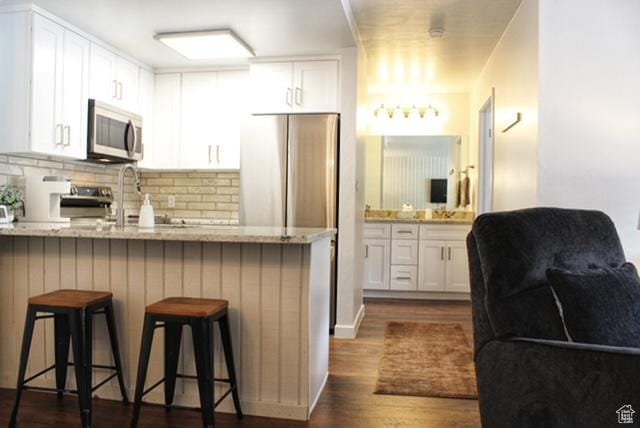 385 S Vasels Rd Unit 21, Brian Head, UT 84719 - kitchen featuring appliances with stainless steel finishes, a peninsula, white cabinets, and a kitchen bar