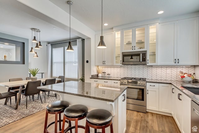 11211 S Clear Blue Dr, South Jordan, UT 84009 - kitchen featuring stainless steel appliances, light wood-style floors, dark stone countertops, decorative backsplash, and a breakfast bar area