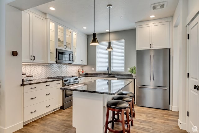 11211 S Clear Blue Dr, South Jordan, UT 84009 - kitchen featuring stainless steel appliances, a sink, a kitchen bar, light wood-type flooring, and white cabinetry