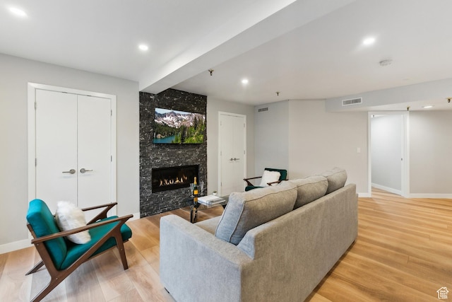 living room with visible vents, light wood-style floors, and a fireplace