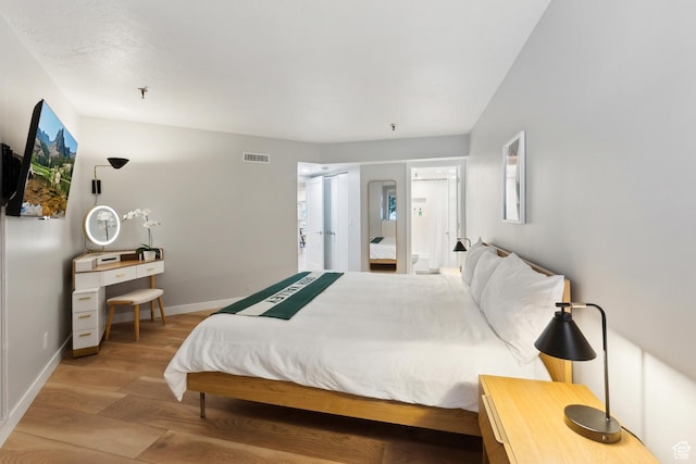 bedroom with baseboards, wood finished floors, and visible vents