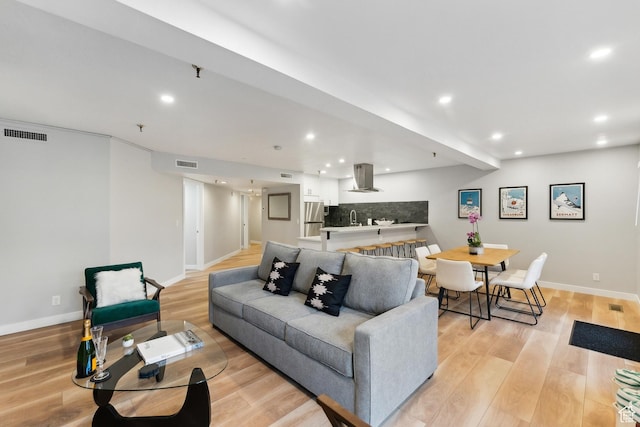 living room with recessed lighting, light wood-style flooring, and visible vents
