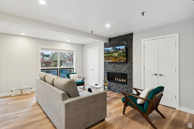 living room featuring recessed lighting, light wood-type flooring, and a fireplace