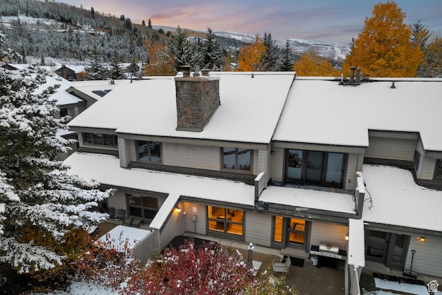 snow covered back of property featuring a chimney