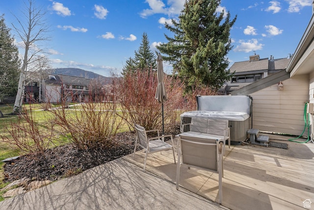 deck featuring a hot tub, a mountain view, and a patio area
