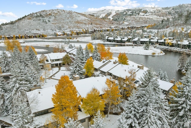 snowy aerial view featuring a residential view and a water and mountain view