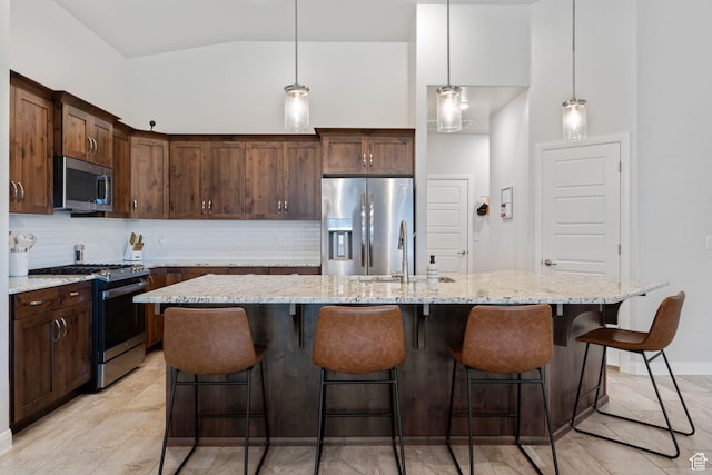 2084 E Sunshine Trl, St George, UT 84790 - kitchen featuring appliances with stainless steel finishes, a sink, decorative backsplash, light stone countertops, and an island with sink