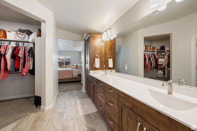 2084 E Sunshine Trl, St George, UT 84790 - ensuite bathroom with double vanity, baseboards, vaulted ceiling, and a walk in closet