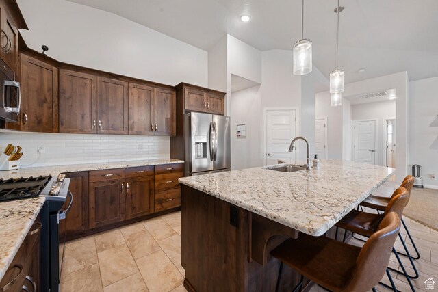 2084 E Sunshine Trl, St George, UT 84790 - kitchen with stainless steel appliances, a sink, tasteful backsplash, light stone countertops, and a breakfast bar