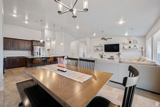 dining area featuring vaulted ceiling and ceiling fan with notable chandelier