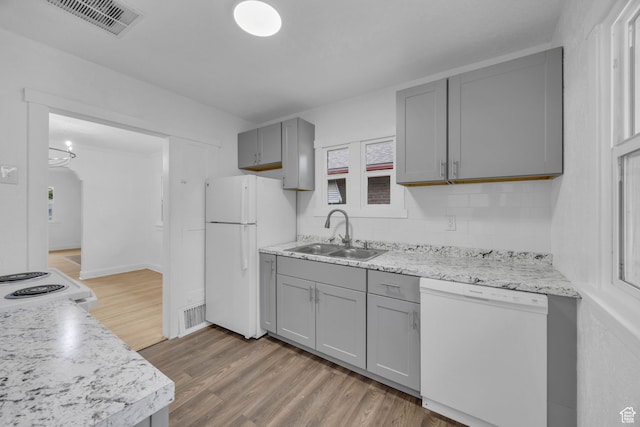 kitchen with hardwood / wood-style flooring, gray cabinetry, backsplash, sink, and white appliances