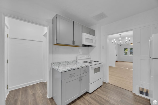 kitchen with white appliances, gray cabinetry, light wood-type flooring, decorative backsplash, and an inviting chandelier