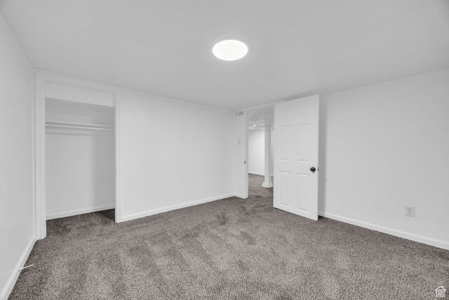 unfurnished bedroom with dark colored carpet and a closet