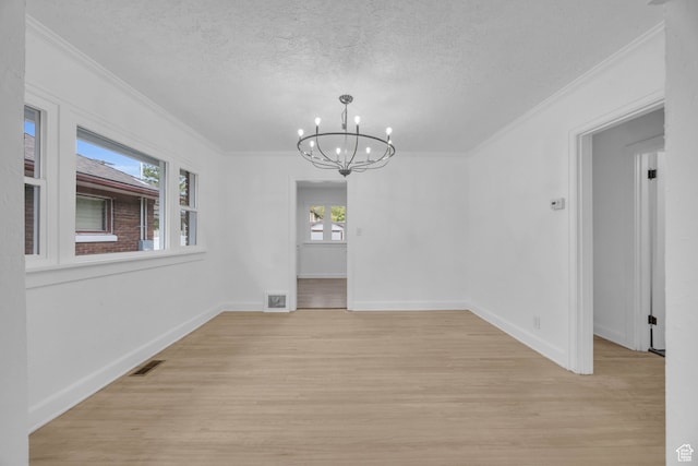 unfurnished dining area with ornamental molding, light hardwood / wood-style flooring, a textured ceiling, and a chandelier