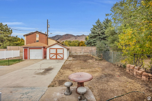 view of yard featuring a mountain view, a storage unit, and a garage