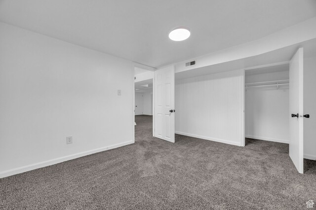 unfurnished bedroom with a closet and dark carpet