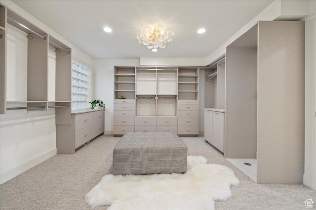 walk in closet with light colored carpet and a chandelier