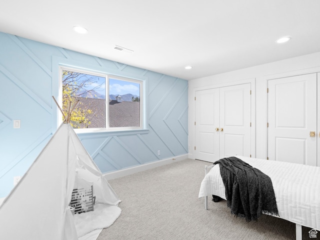 carpeted bedroom featuring a decorative wall, recessed lighting, and a closet