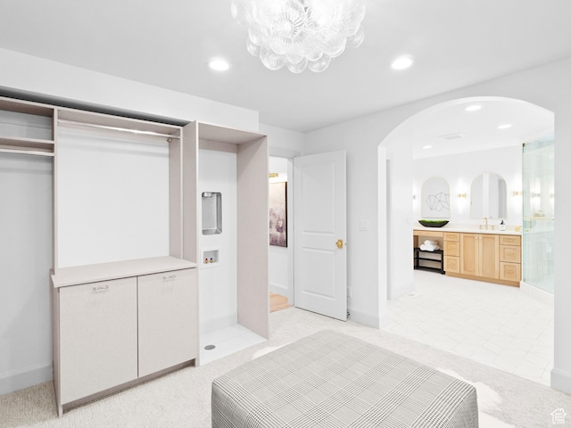 unfurnished bedroom with arched walkways, a chandelier, recessed lighting, baseboards, and light carpet