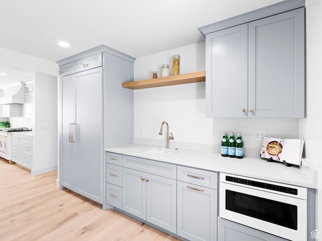 kitchen featuring open shelves, a sink, light wood-style floors, gray cabinets, and recessed lighting