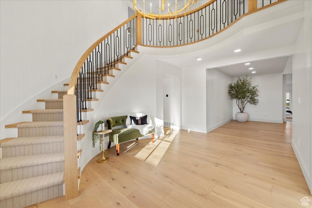 stairs with a high ceiling, wood finished floors, baseboards, and recessed lighting