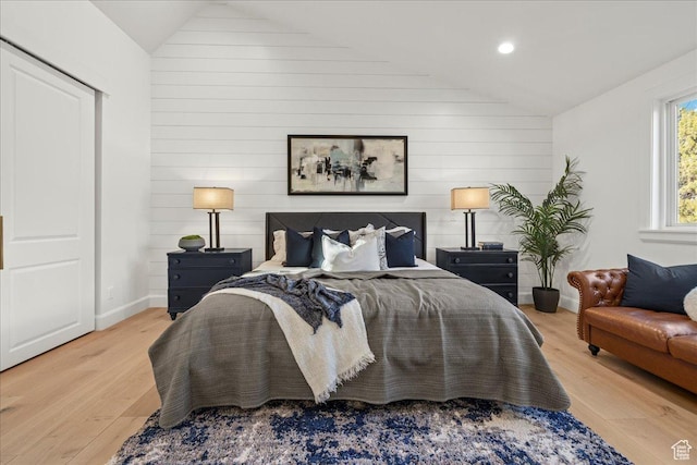 bedroom featuring lofted ceiling, wood finished floors, and wooden walls