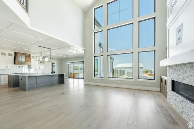 unfurnished living room featuring a fireplace, light hardwood / wood-style flooring, and a high ceiling