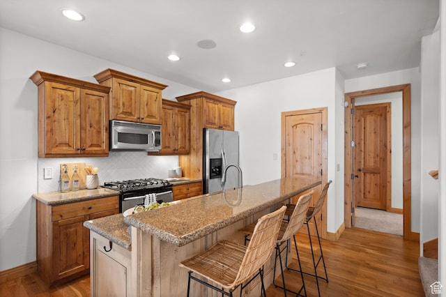3025 Lower Saddleback Rd Unit 13, Park City, UT 84098 - kitchen with appliances with stainless steel finishes, a kitchen breakfast bar, decorative backsplash, light stone counters, and a center island with sink