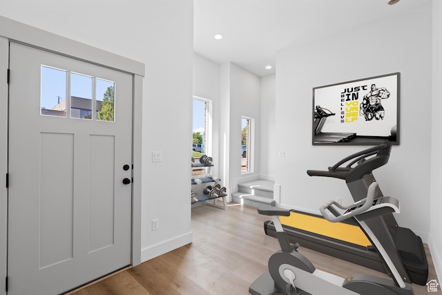 exercise area featuring baseboards, light wood finished floors, and recessed lighting