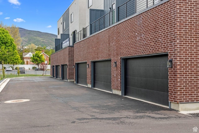 view of side of home featuring a mountain view, a garage, brick siding, and driveway