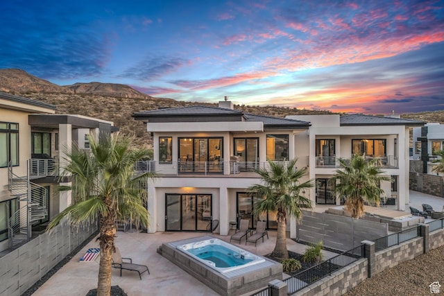 1498 W Torrey Pines Rd, Hurricane, UT 84737 - back of house at dusk with a patio, stucco siding, an outdoor hot tub, and a balcony