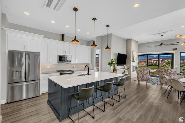 1498 W Torrey Pines Rd, Hurricane, UT 84737 - kitchen featuring stainless steel appliances, a sink, white cabinetry, decorative backsplash, and light wood-type flooring