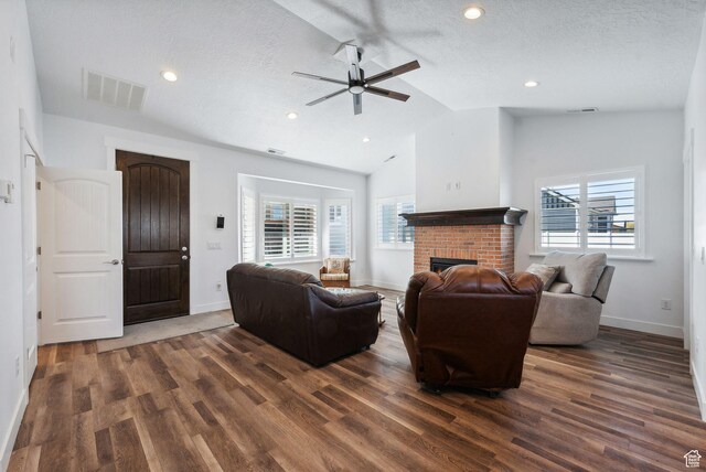 967 W Yamada Ct S, Syracuse, UT 84075 - living room with vaulted ceiling, a ceiling fan, dark wood-style floors, a fireplace, and a textured ceiling