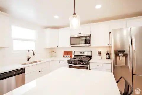 1065 E 22nd St, Ogden, UT 84401 - kitchen with appliances with stainless steel finishes, a sink, white cabinetry, light countertops, and decorative light fixtures