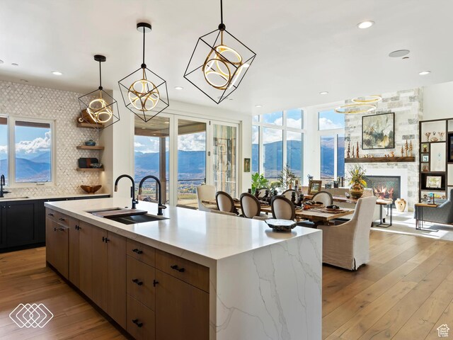 5731 E Porcupine Ridge Dr N, Eden, UT 84310 - kitchen featuring a sink, light wood finished floors, a stone fireplace, an island with sink, and recessed lighting