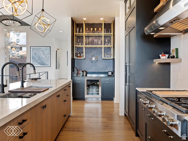 5731 E Porcupine Ridge Dr N, Eden, UT 84310 - kitchen with wall chimney range hood, a sink, wine cooler, stainless steel gas cooktop, and light wood finished floors