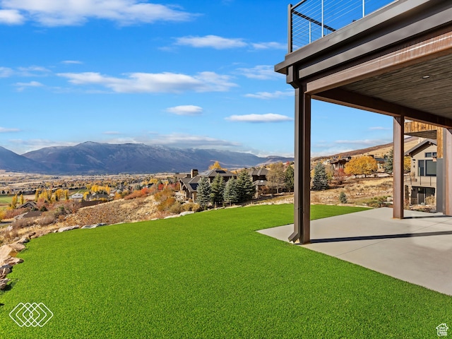 view of yard featuring a patio area, a mountain view, and a balcony