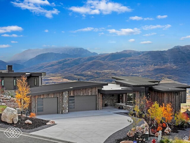 5731 E Porcupine Ridge Dr N, Eden, UT 84310 - view of front of property with a mountain view, concrete driveway, a garage, and board and batten siding