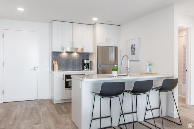 2303 Deer Hollow Rd Unit 1236, Park City, UT 84060 - kitchen featuring light hardwood / wood-style flooring, white cabinetry, a breakfast bar, and stainless steel appliances