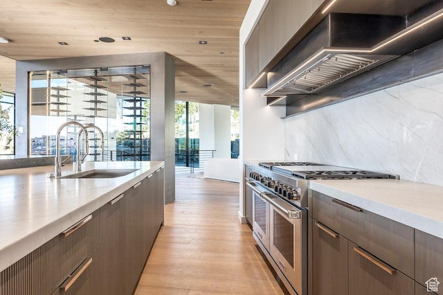 3821 Pinnacle Sky Loop, Park City, UT 84098 - kitchen featuring range with two ovens, wall chimney range hood, a sink, light wood-style flooring, and tasteful backsplash