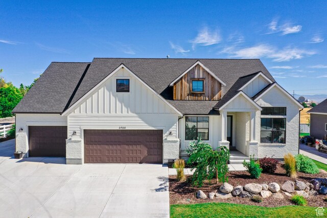 modern inspired farmhouse featuring driveway, a shingled roof, a garage, and board and batten siding