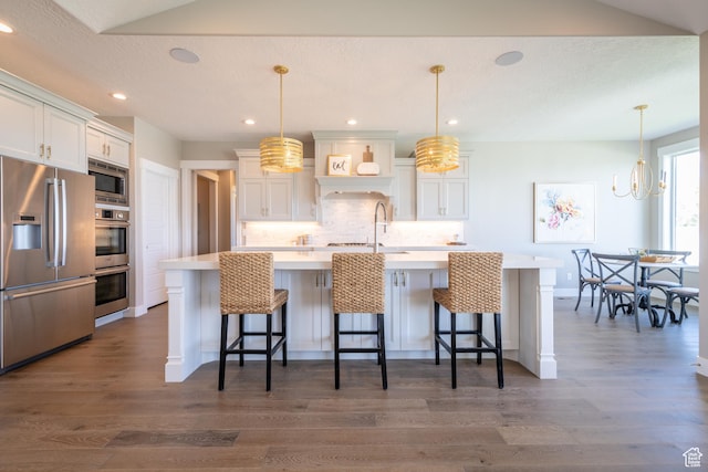 12751 S Harvest Ln W Unit 6, Riverton, UT 84096 - kitchen with light countertops, a kitchen breakfast bar, stainless steel appliances, dark wood finished floors, and backsplash