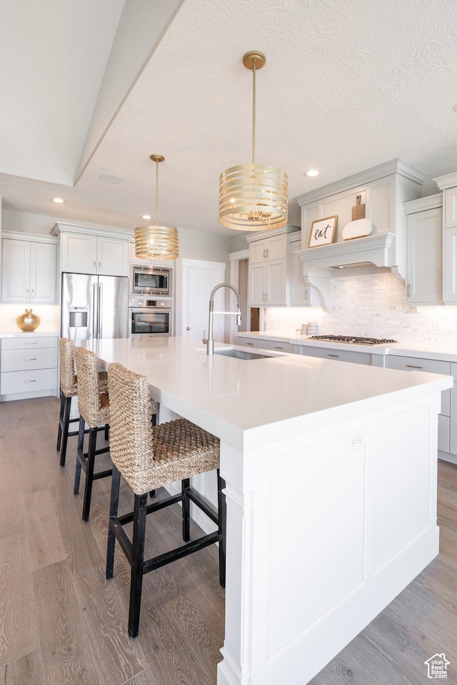 12751 S Harvest Ln W Unit 6, Riverton, UT 84096 - kitchen featuring decorative backsplash, light countertops, stainless steel appliances, light wood-style floors, and a large island