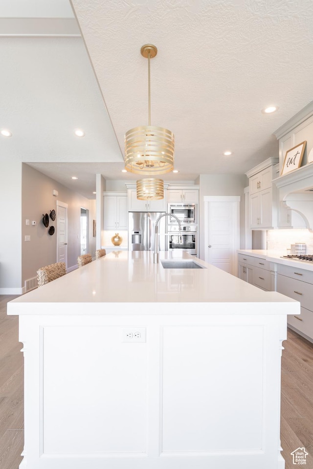 12751 S Harvest Ln W Unit 6, Riverton, UT 84096 - kitchen with light countertops, appliances with stainless steel finishes, light wood-style floors, and a large island