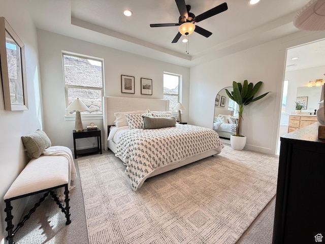 bedroom with a tray ceiling, light colored carpet, baseboards, and recessed lighting