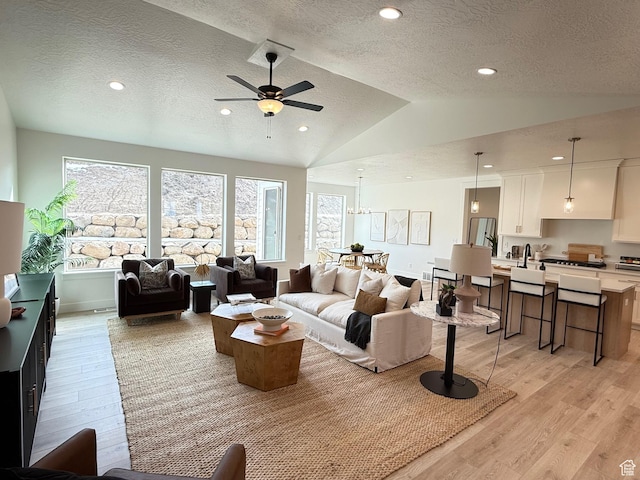living area featuring vaulted ceiling, a textured ceiling, recessed lighting, and light wood-style floors