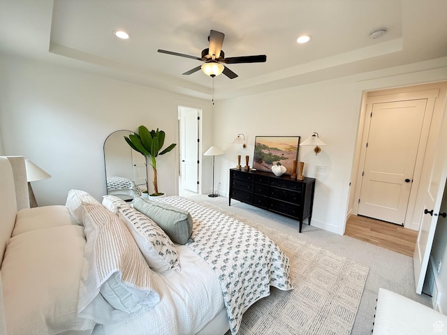carpeted bedroom featuring baseboards, a raised ceiling, and recessed lighting